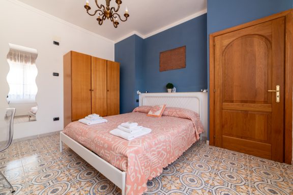 Camera da letto con letto matrimoniale, armadio in legno e pareti blu. Linens bianchi.