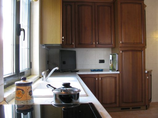 Cucina moderna con ante in legno, piano cottura e finestre luminose.