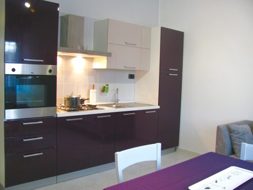 Cucina moderna con armadietti scuri, piano cottura e zona pranzo.